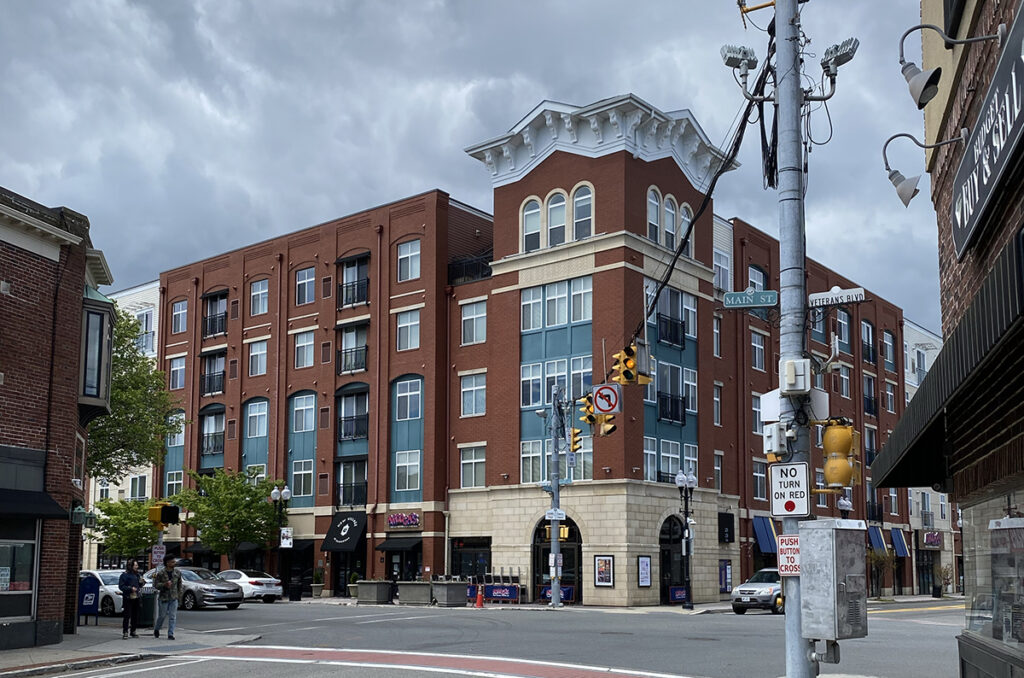 A red brick building on a busy street at the heart of Patchogue.